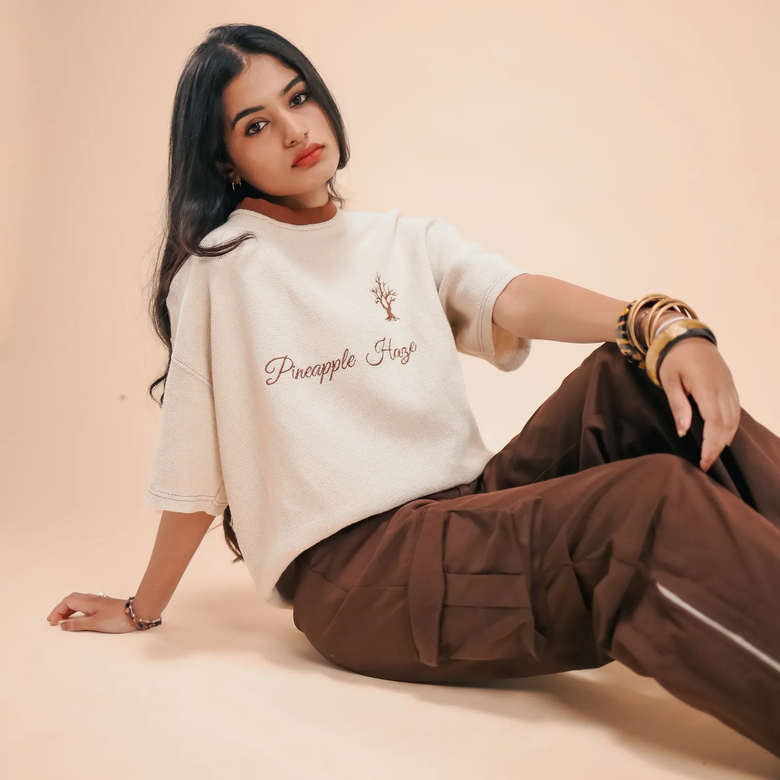 Leaning back on one arm in the Pineapple Haze tee